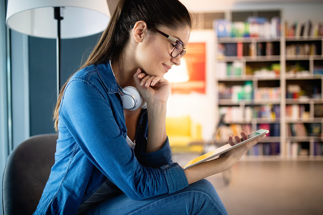 Beautiful happy student woman holding tablet while smiling